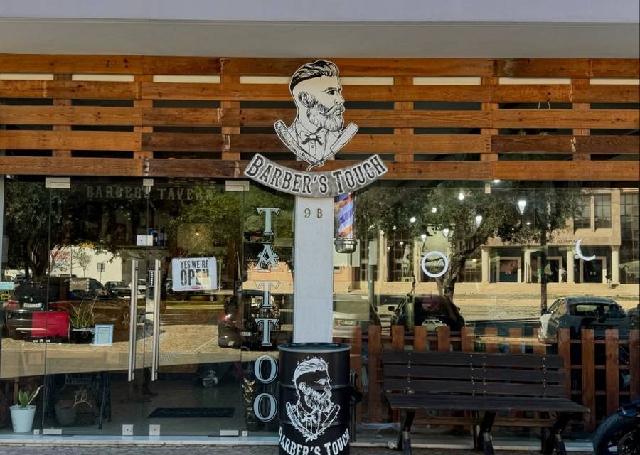 Fachada da Barber's Touch, com a tabuleta e o banco de madeira à entrada